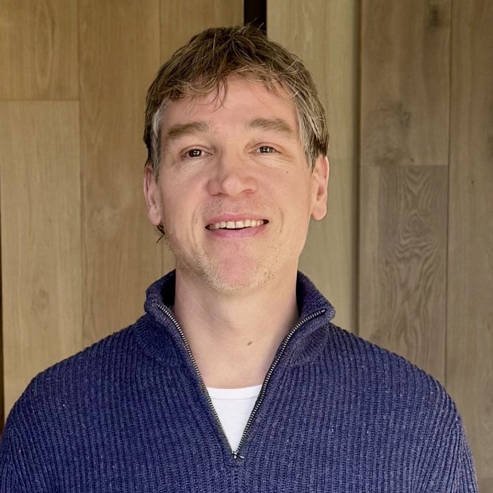 headshot of a man sanding against a backdrop of engineered wooden boards