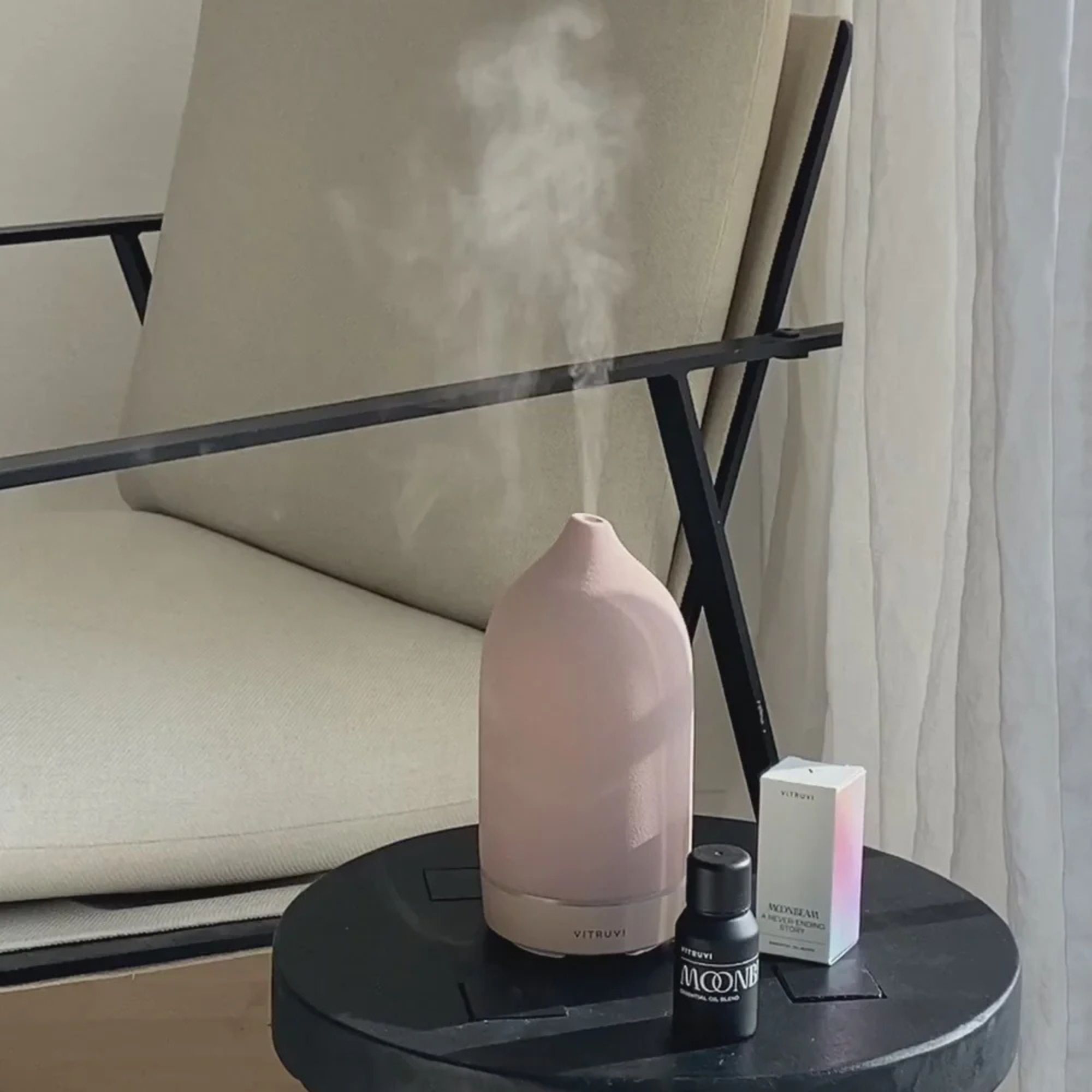 Vitruvi Stone on a table in front of a cream armchair.