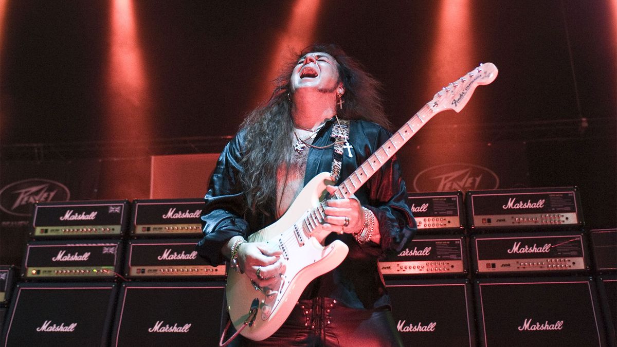 Yngwie Malmsteen plays electric guitar in front a Marshall amp stack