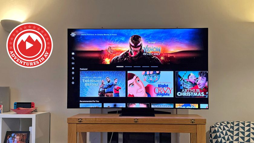 A 65-inch Samsung TV on a wooden stand in a living room. On the screen is the homepage of Sony Pictures Core from the PS5, with a big banner for the Venom: The Last Dance movie.