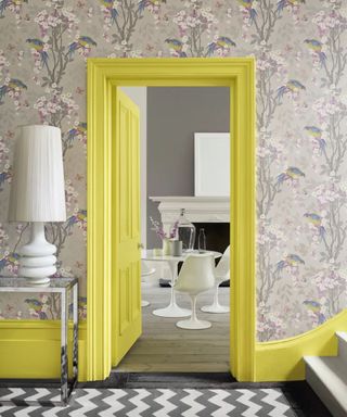 Doorway painted yellow with neutral colored wallpaper around and dining room beyond