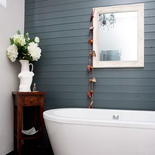 bathroom with blue panel wall bathtub and flower pot wooden table