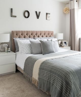 white bedroom with bed with cushions and table lamp
