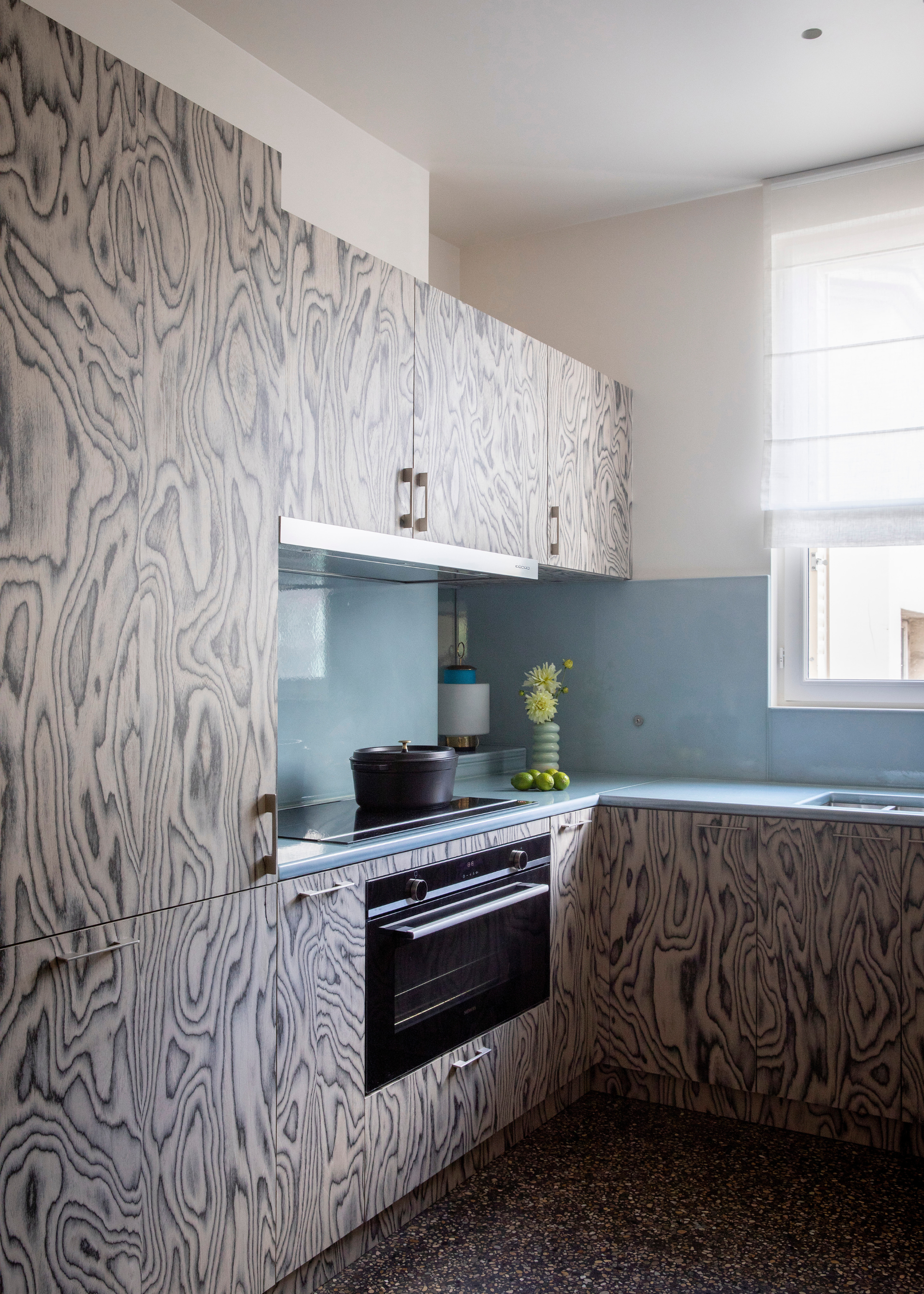 small kitchen with black and white printed veneer cabinets and light blue counters and backsplash