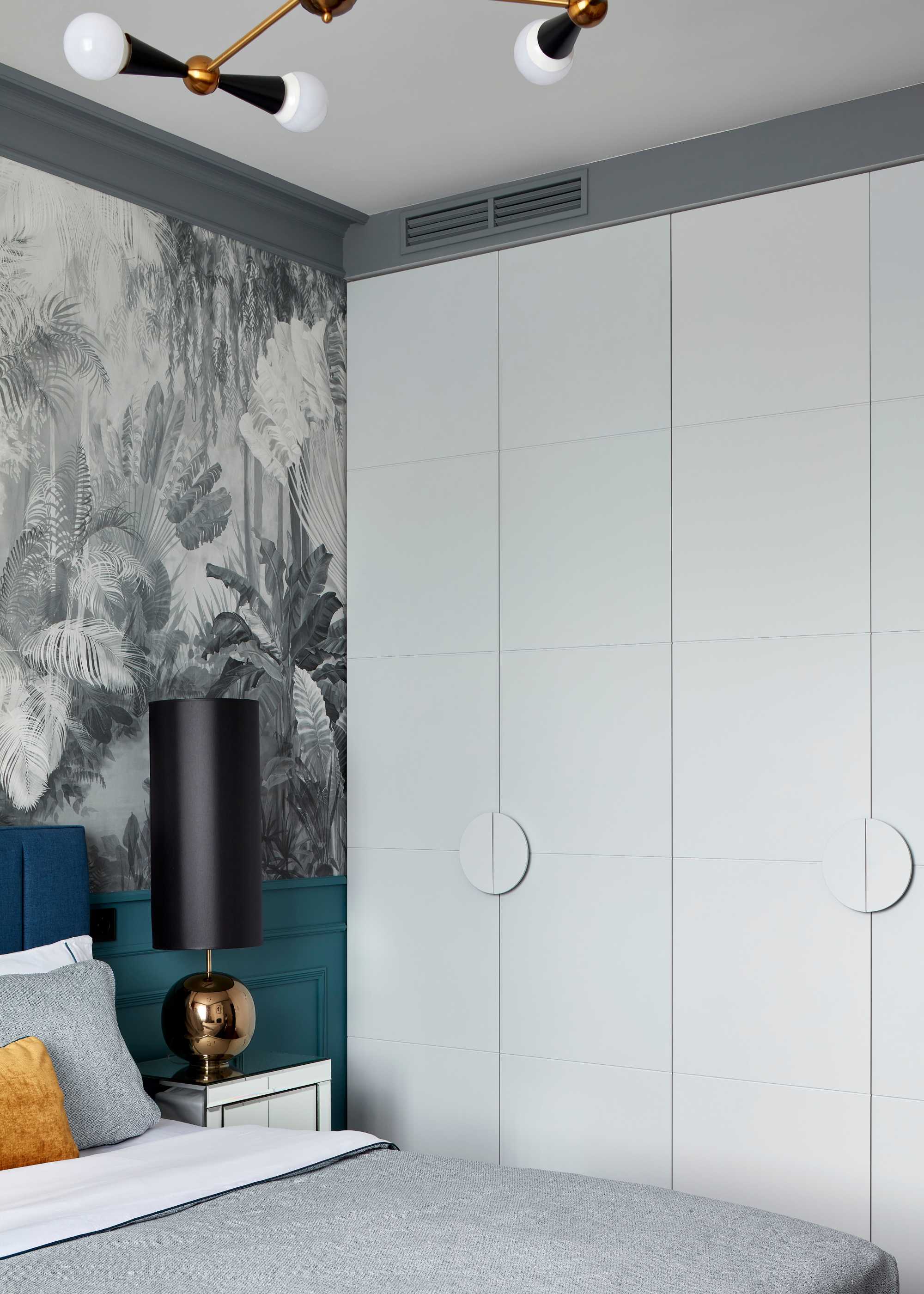 A light blue bedroom with a mural wallpaper and a side table