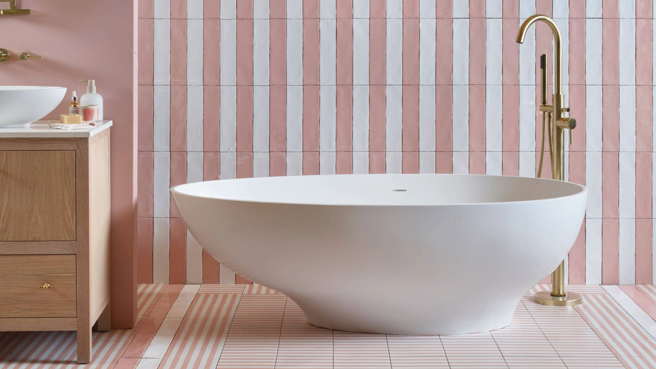 Bathroom tiling idea for small bathroom where striped pink and white tiles are placed behind a freestanding bath