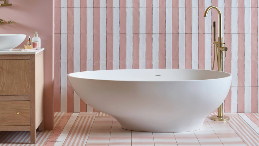 Bathroom tiling idea for small bathroom where striped pink and white tiles are placed behind a freestanding bath