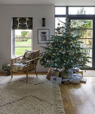 A sitting room with a parquet floor, rug and a decorated Christmas tree by the glass garden doors. A three bedroom bungalow converted into a four bedroom barn style family home