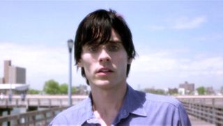 Jared Leto standing on a pier with a blue shirt on in Requiem For A Dream.