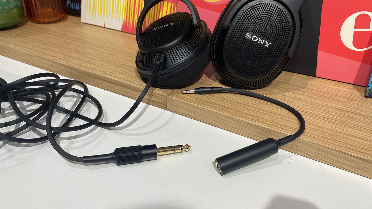 A black pair of Sony MDR-MV1 wired headphones on a wooden surface with their cable showing.