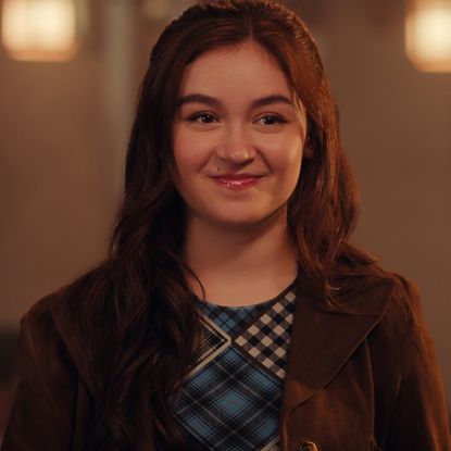 anna cathcart in xo kitty season 2 smiling and wearing a suede jacket and printed top