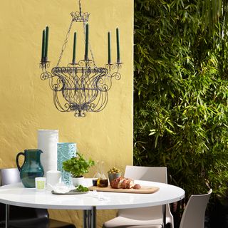 garden with yellow painted walls white round table wirework chandelier