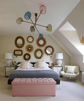 An example of bedroom lighting ideas showing an oversized colorful ceiling lamp in a white bedroom with a blue bed in front of a wall with mirrors
