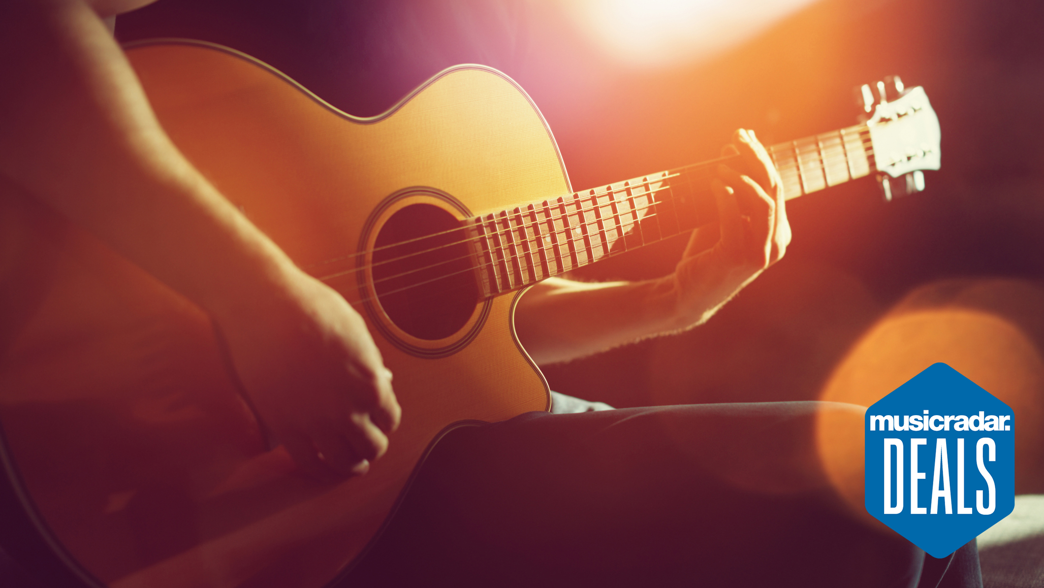 Close up of a person holding an acoustic guitar bathed sunlight