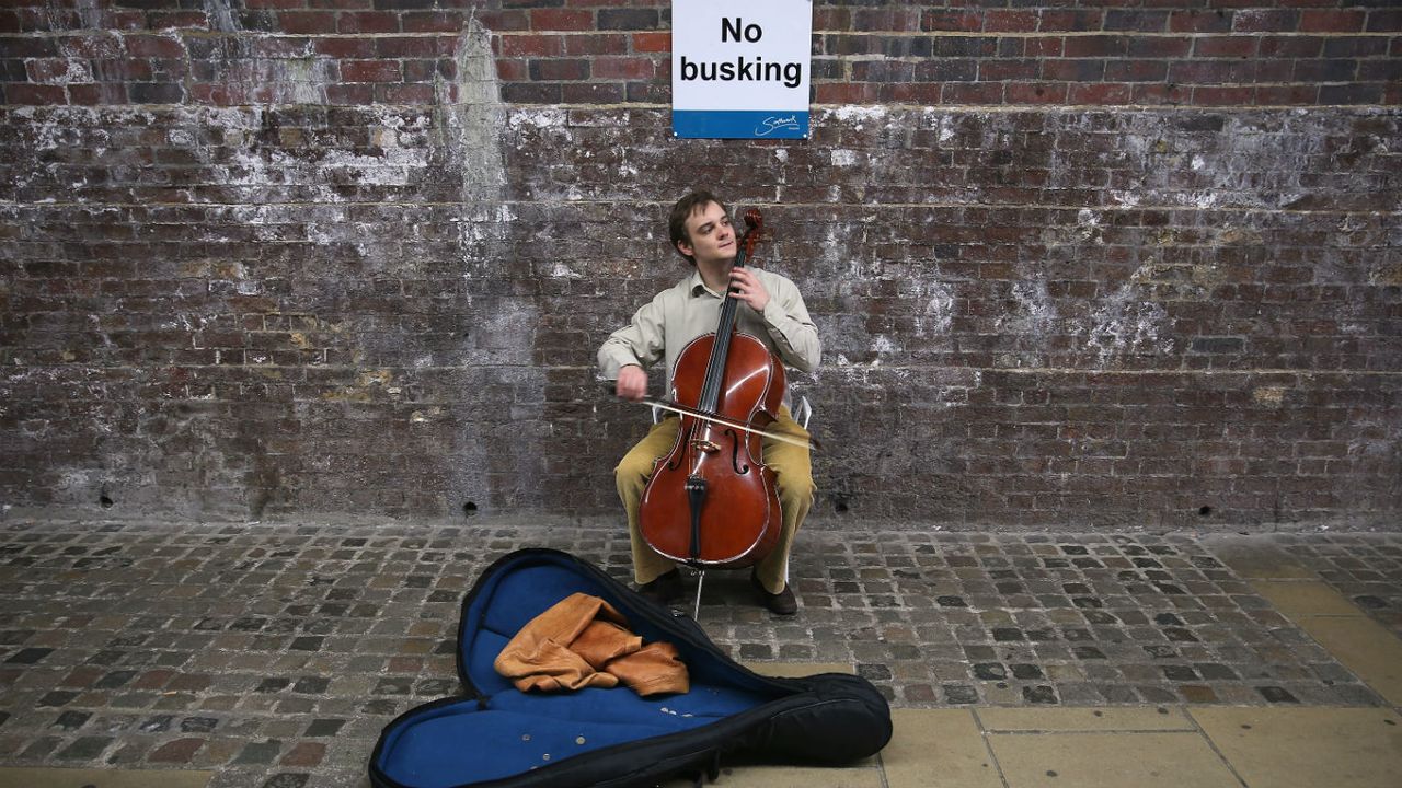 A busker under a bridge near the Thames River 