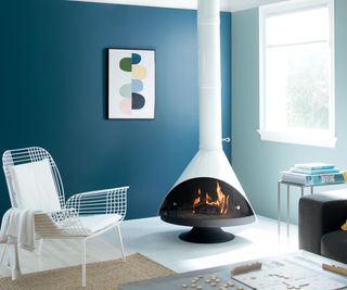 living space with dark blue wall, light blue wall, modern fire with chimney, white metal chair, white flooring and jute rug