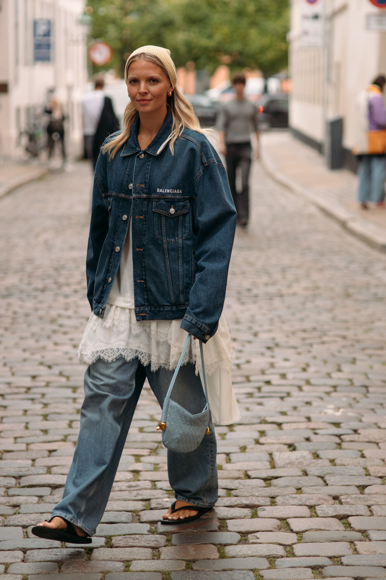 woman wearing denim jacket, white lace dress, and jeans