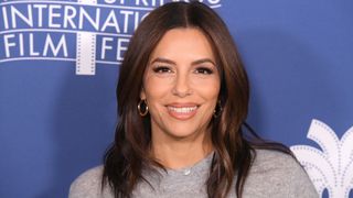 Eva Longoria smiling with brunette hair and wearing a grey top