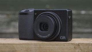 Et kompaktkamera av typen Ricoh GR IIIx på en bordplate.