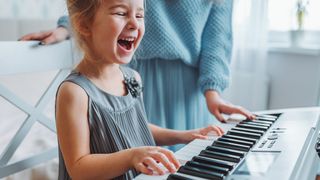 Young girl smiling whilst playing a keyboard