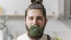 Man has whole head of broccoli in his mouth