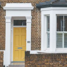 A front porch of a town house with a sunny yellow front door