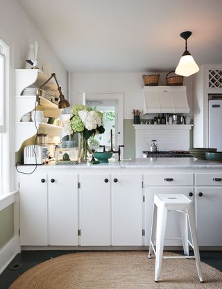 white kitchen with white kitchen stool and natural round rattan rug