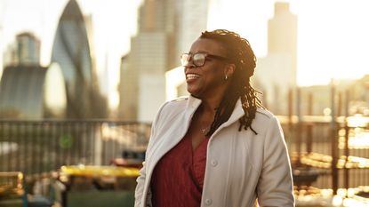 A smiling female executive on the roof of a building in a big city with the skyline in the background. 