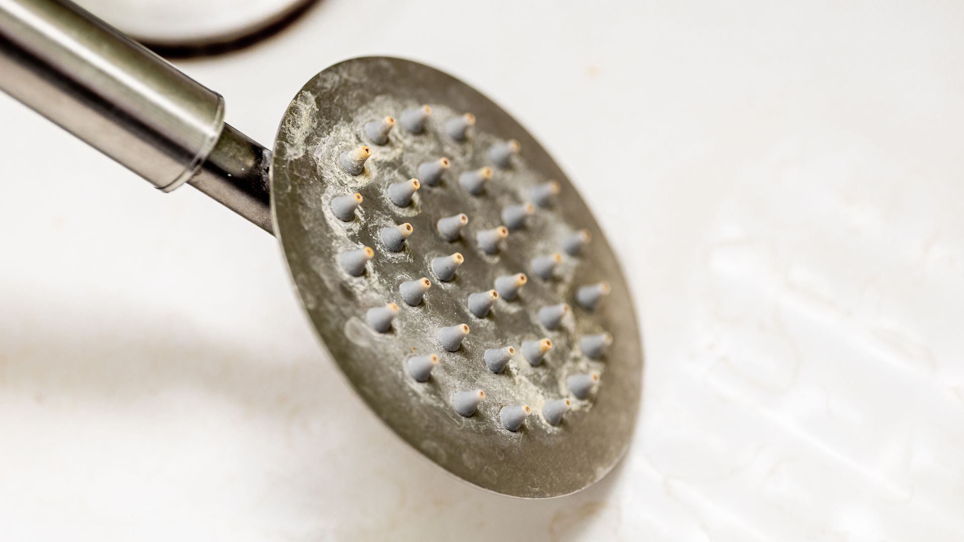 picture of a chrome shower head with limescale on it