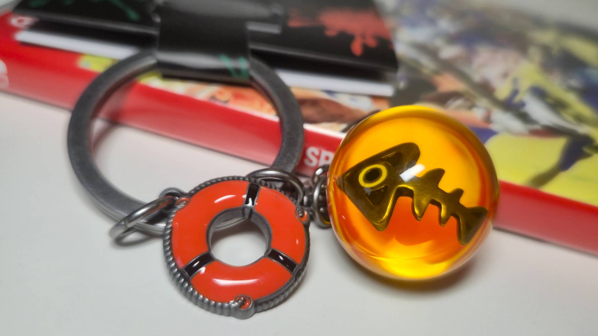 Close up of the Salmon Run Splatoon 3 keychain sitting on a Switch copy of Splatoon 3.