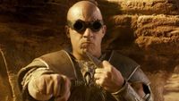 Vin Diesel breaks out his weapons while taking cover behind a desert rock formation in Riddick.