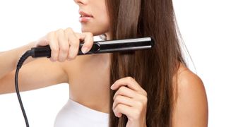 A woman straightening her hair with a hair straigthener