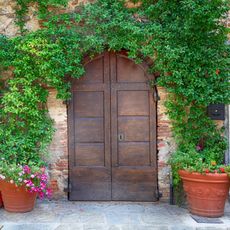 garden with brick wall, aged wooden door and clay pots