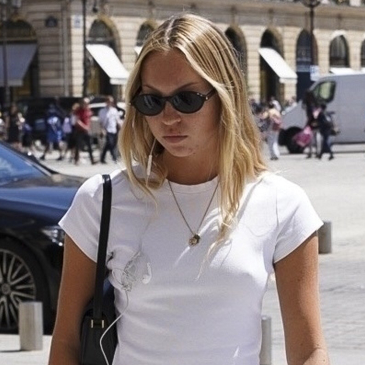 Lila Moss in Paris wearing a white T-shirt, linen miniskirt, and black ballet flats.