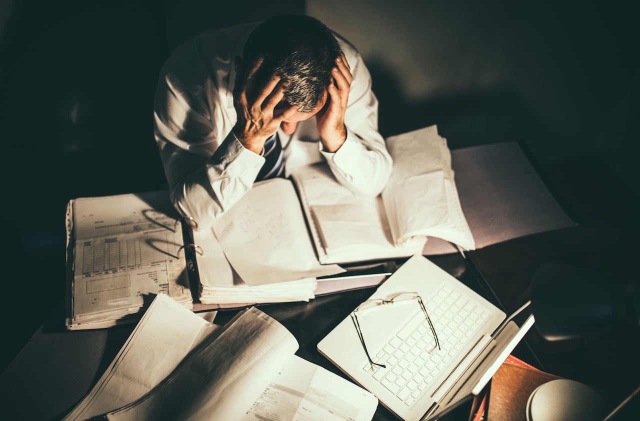 Exhausted senior man working after hours in his office to complete the job that must be done.