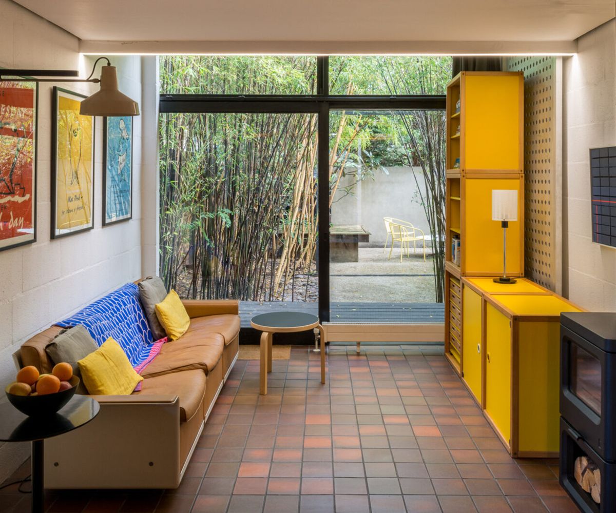 Before shots of 1 970s style single storey london house before a renovation and first floor extension. There is a lack of natural light but pops of bright yellow interiors a terracotta tiled floor and built in log burner