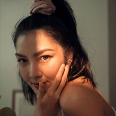 a model in the light, touching her face