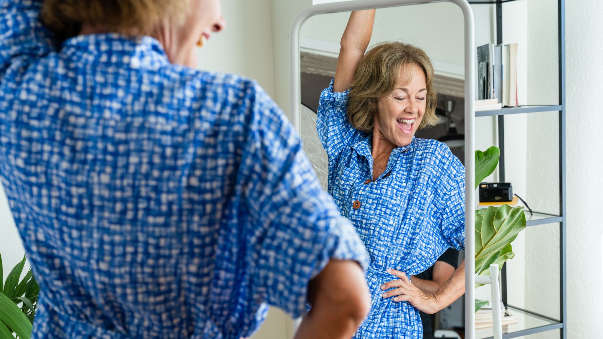 A happy woman celebrates in front of a mirror