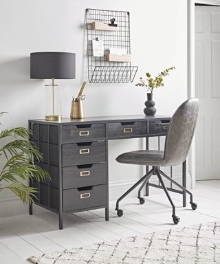 A home office with wire wall organizer and desk containing filing compartments with brass card holders for labeling