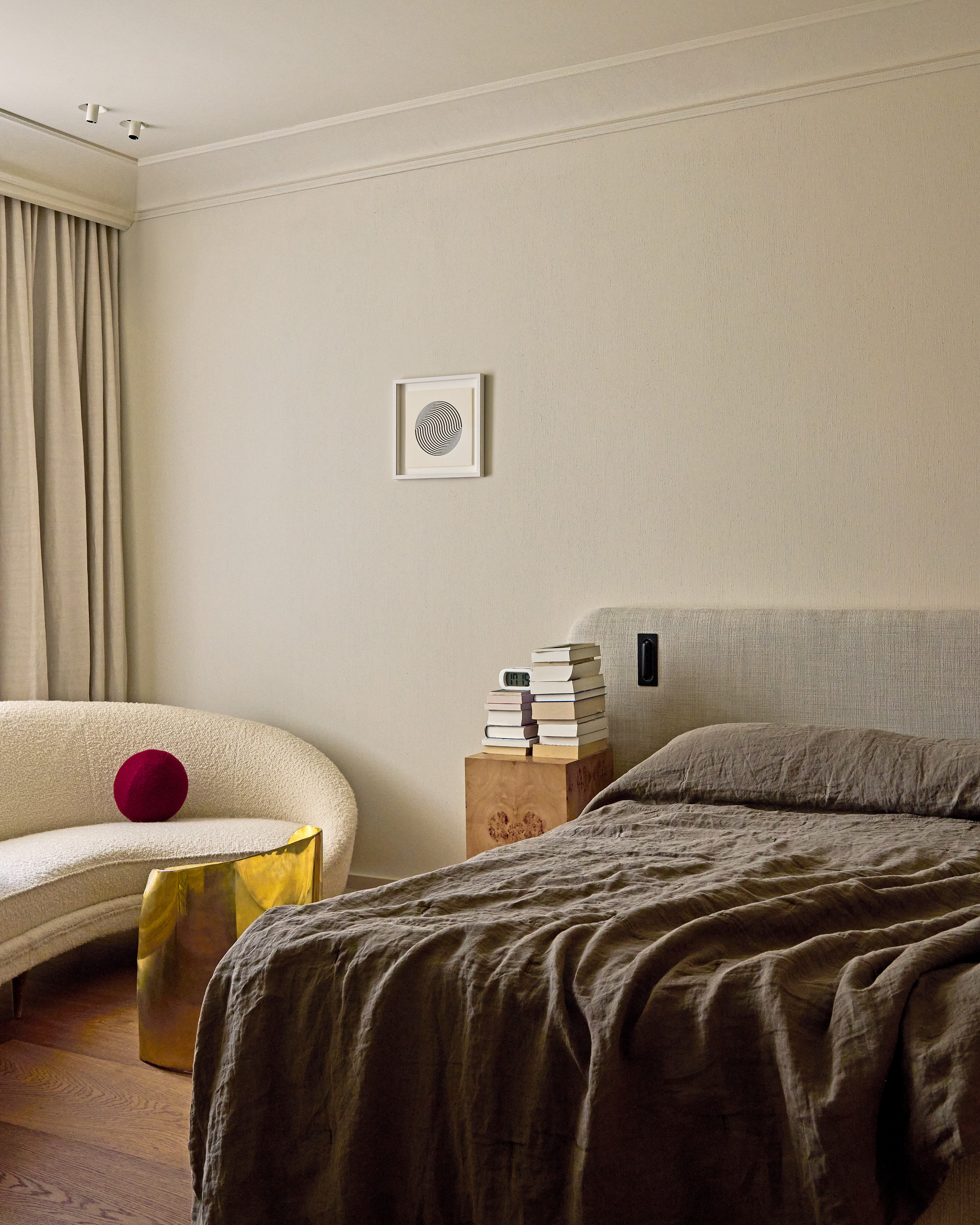 White bedroom with grey bed, white curved sofa and gold chair