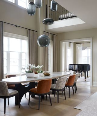 Modern dining room space with round pendant, oval table, and flowers atop