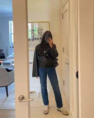 A woman taking a mirror selfie and holding a Loewe Puzzle bag.