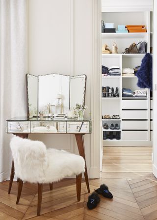 Venetian dressing table and mirror in foreground and walk in wardrobe in the background, herringbone floor