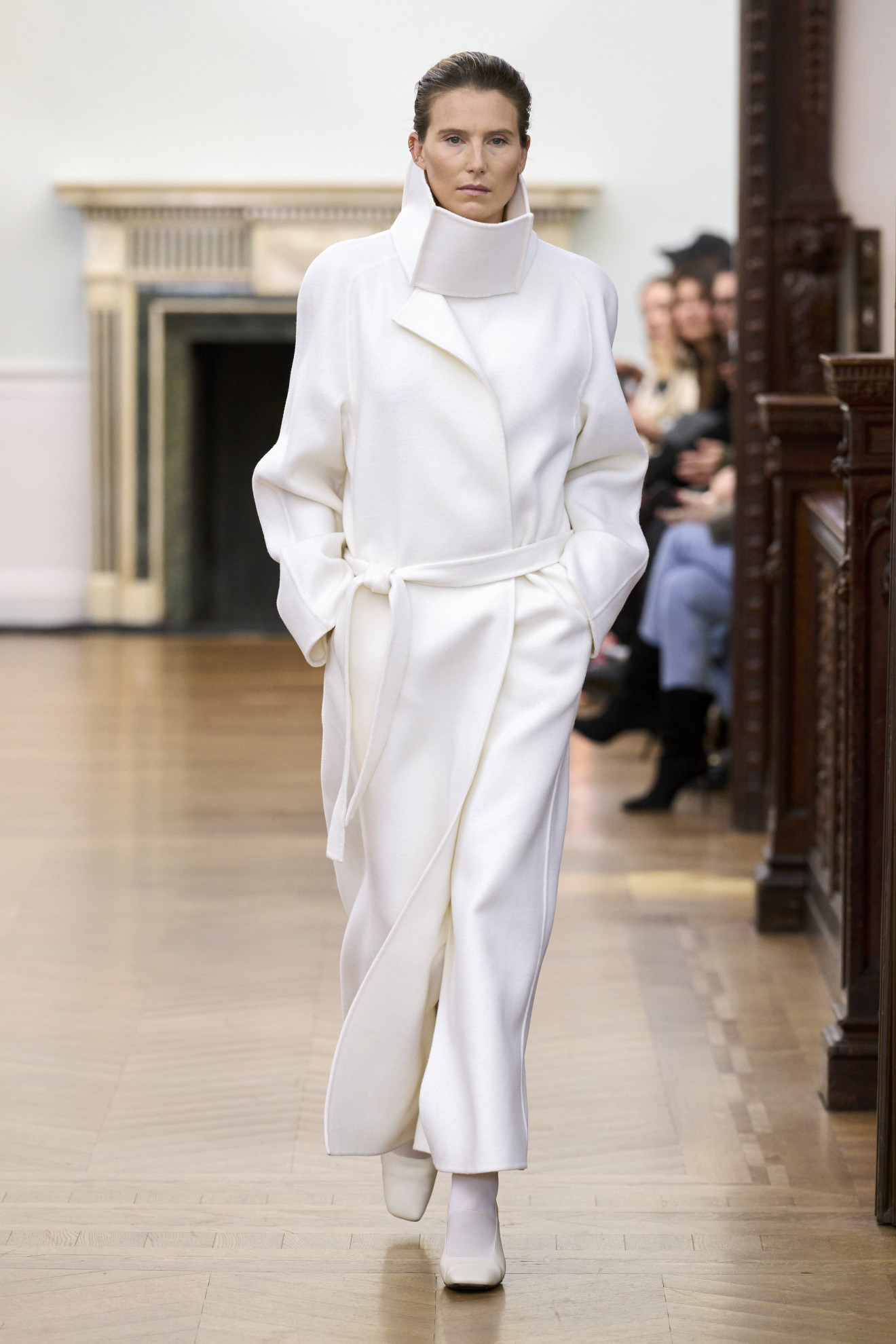 A Bevza model wearing a white, funnel-neck trench coat at the FW24 show.