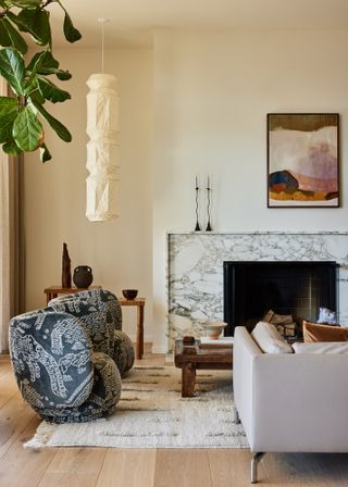Living room with magnolia walls, marble fireplace, grey sofa and blue patterned armchairs