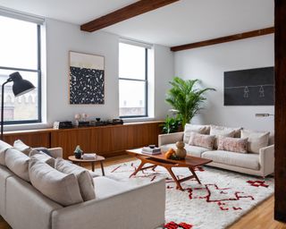 sofa arranging mistakes, white apartment living room with two matching couches, rug, retro coffee table, retro sideboard, art, floor lamp, plants