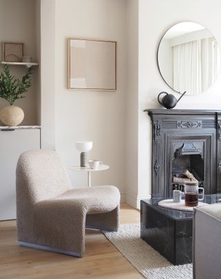 A boucle chair next to black fireplace surround and coffee table