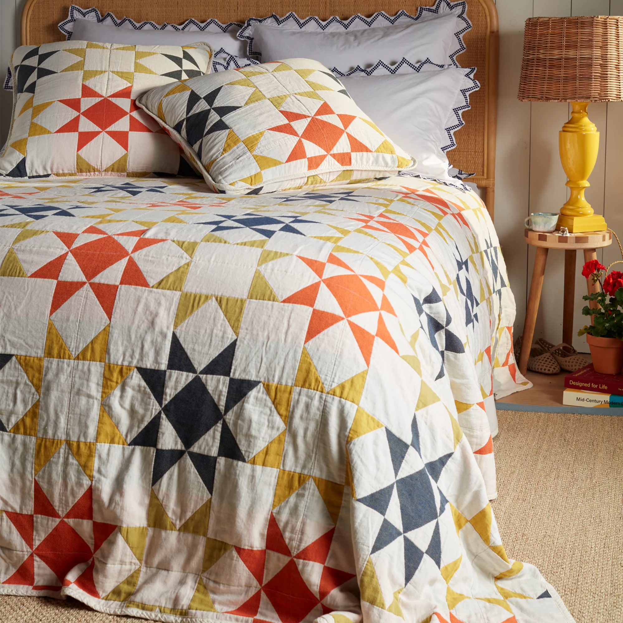 a pinwheel quilt in red, yellow, blue, and white on top of a bed with lots of pillows