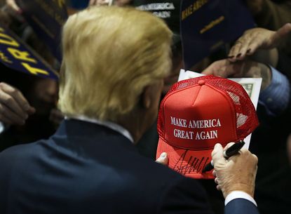Donald Trump signs a hat.