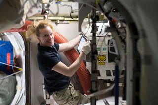 NASA astronaut Kate Rubins works with a Nitrogen/Oxygen Recharge System tank aboard the International Space Station. The tanks are designed to be plugged into the station's existing air supply network to refill the crew's breathable air supply.